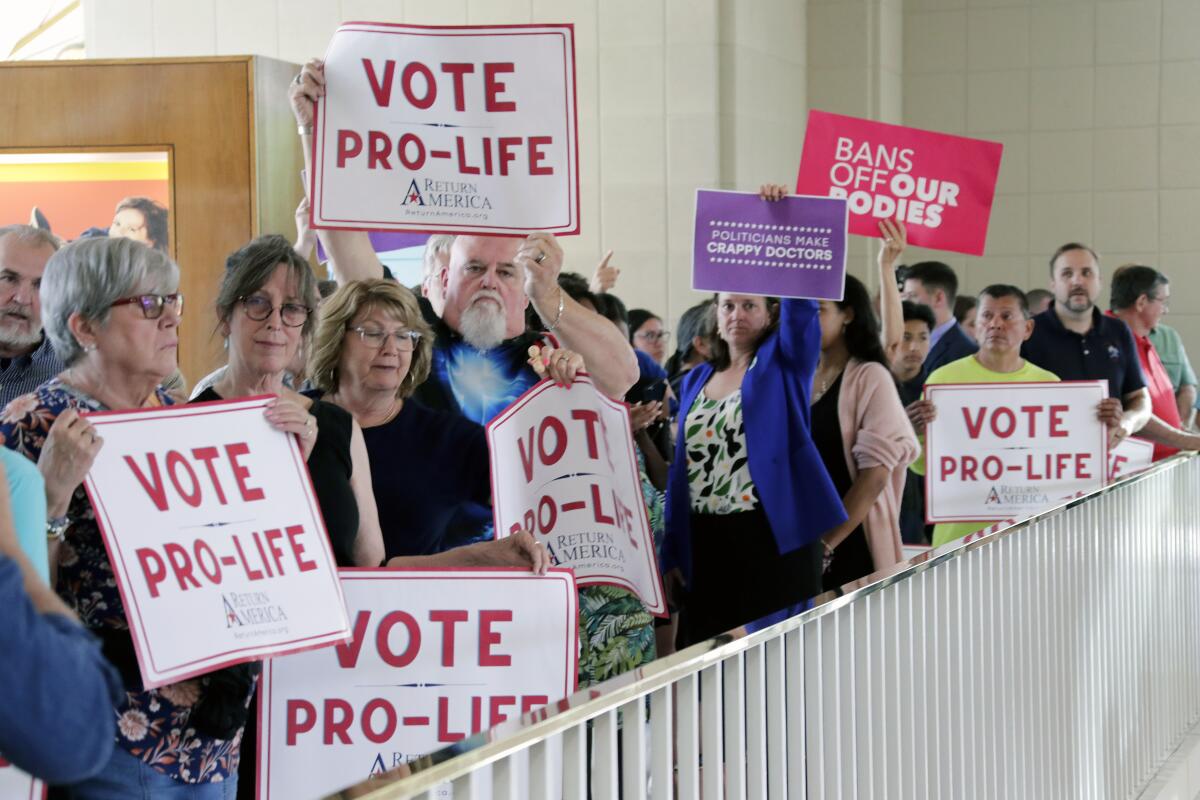 Protesters on both sides of the abortion issue hold signs
