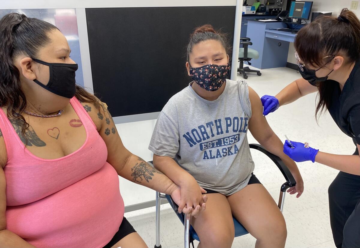 Woman holds the hand of her niece as she gets vaccinated 