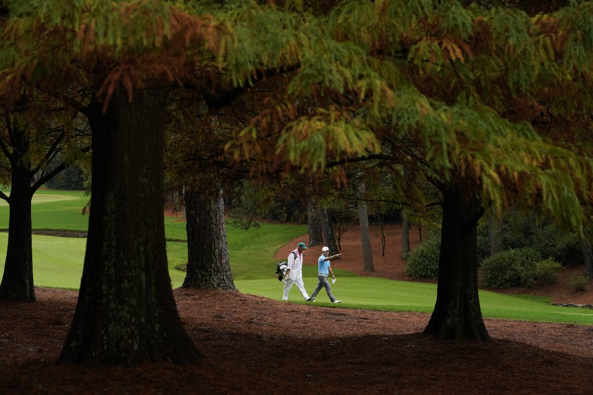 Sung Kang, of South Korea, walks with his caddie along the 13th fairway during a practice round for the Masters golf tournament Wednesday, Nov. 11, 2020, in Augusta, Ga. (AP Photo/Charlie Riedel)