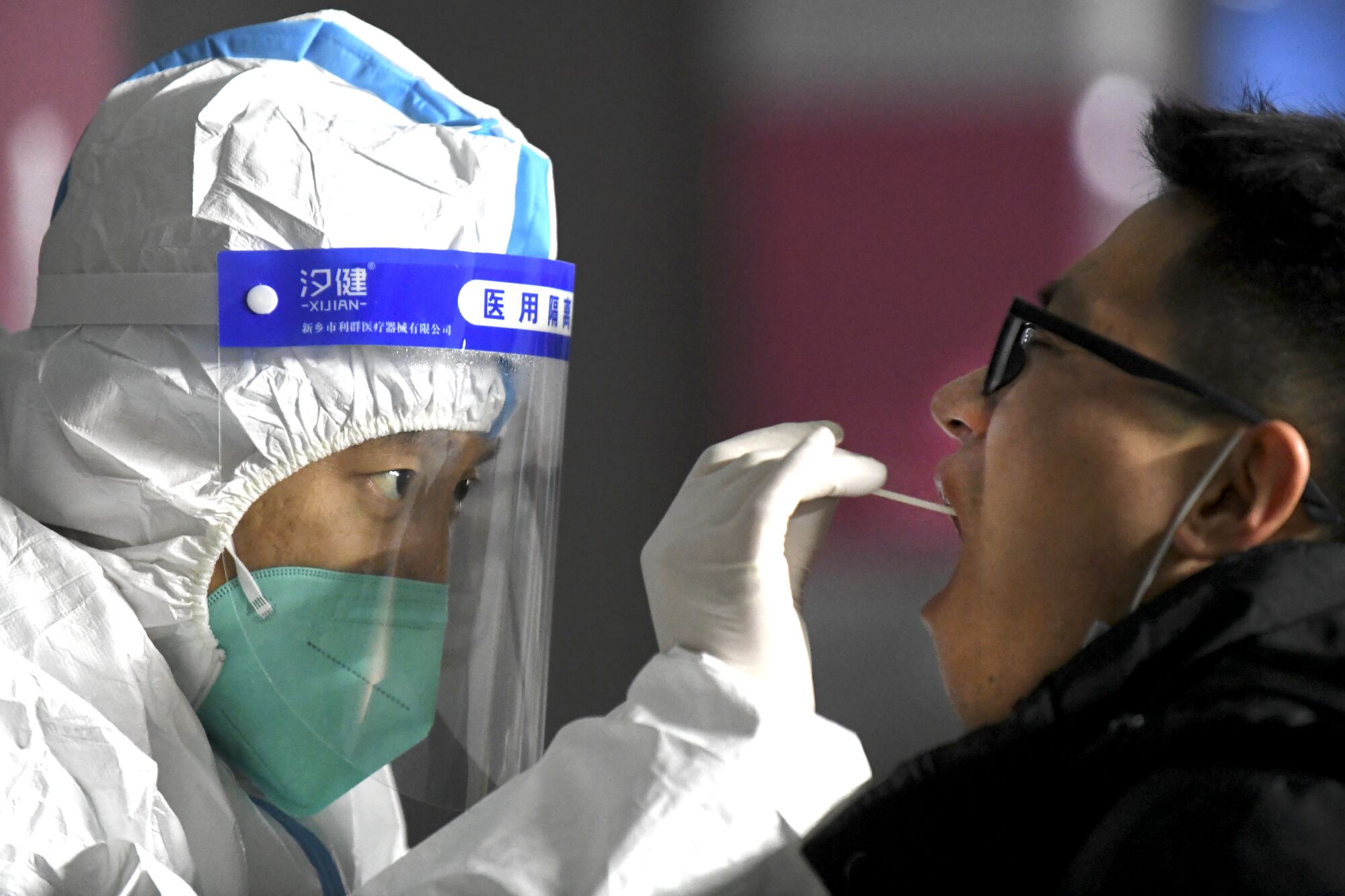 A medical worker in a protective suit takes a swab from a resident in Shijiazhuang, China.