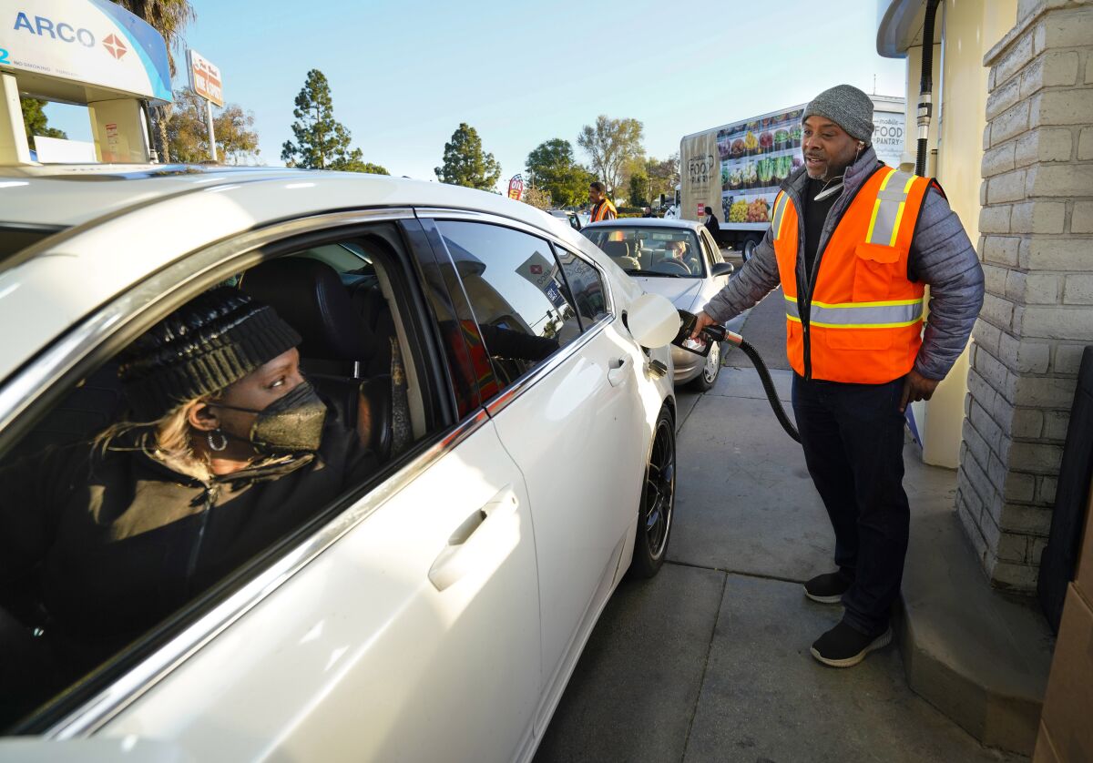 Jocelyn Pride of Chula Vista, left, talks with volunteer James Brown, right, as he fills up her car with gas 