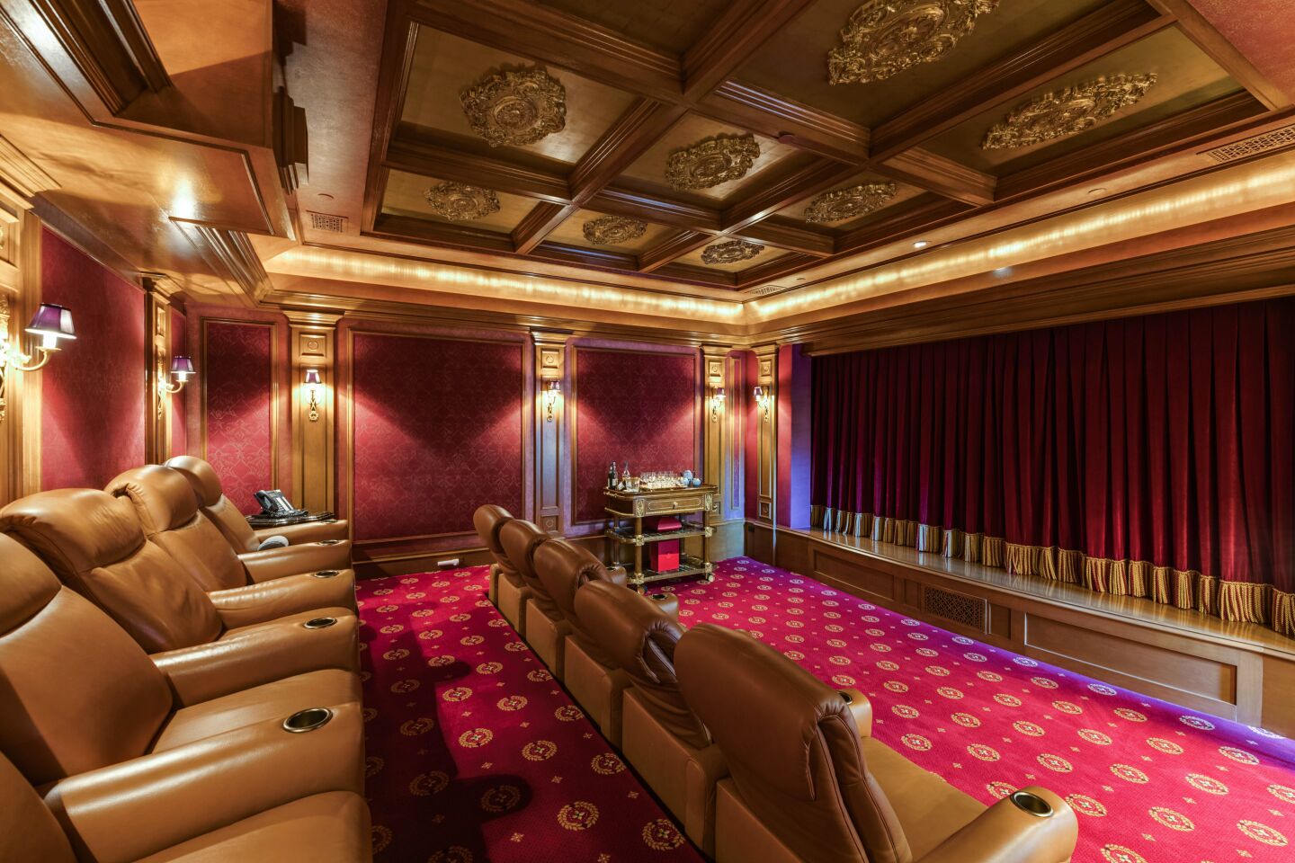 The carpeted movie theater with leather recliners an decorative panels on the ceiling.