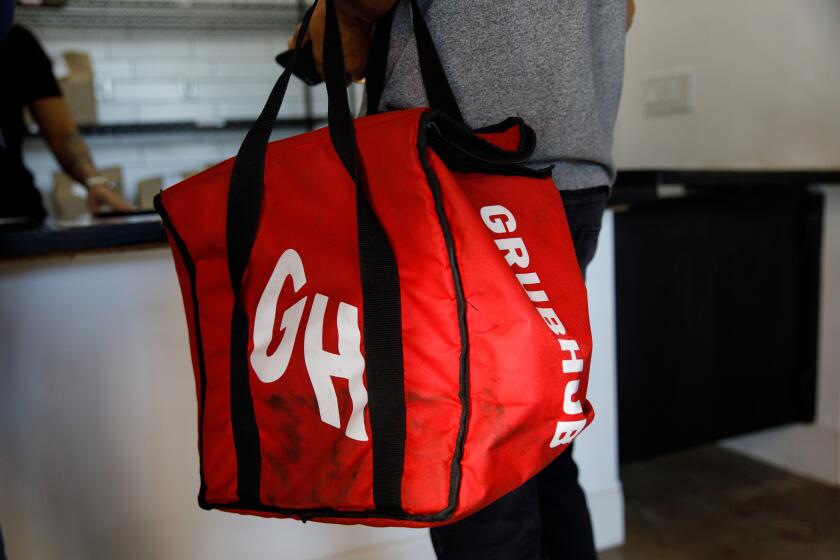 A delivery driver picks up food in a Grubhub bag at Colony on Saturday, January 18, 2020 in Los Angeles, Calif. Colony offers 26 kitchen spaces for rent by restaurants - sometimes referred to as "ghost kitchens" or "virtual kitchens" - where restaurants prepare meals for delivery or pickup to serve consumers using Grubhub, Uber Eats, DoorDash, and other online-based services. (Patrick T. Fallon/ For The Los Angeles Times)
