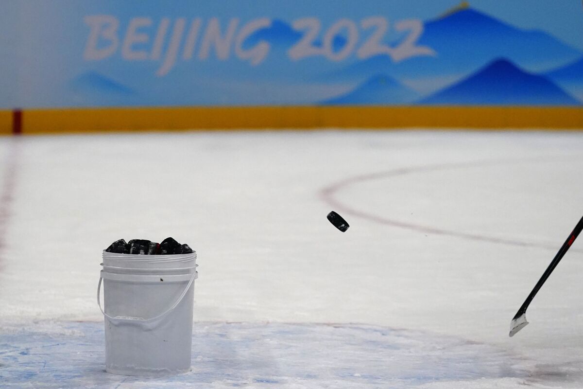 China's Wei Ruike flips a puck into a bucket after a practice session at the National Indoor Stadium at the 2022 Winter Olympics, Tuesday, Feb. 1, 2022, in Beijing. (AP Photo/Matt Slocum)
