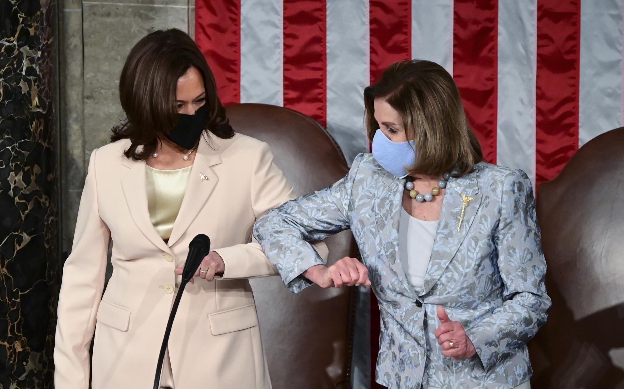 Two women bump elbows.