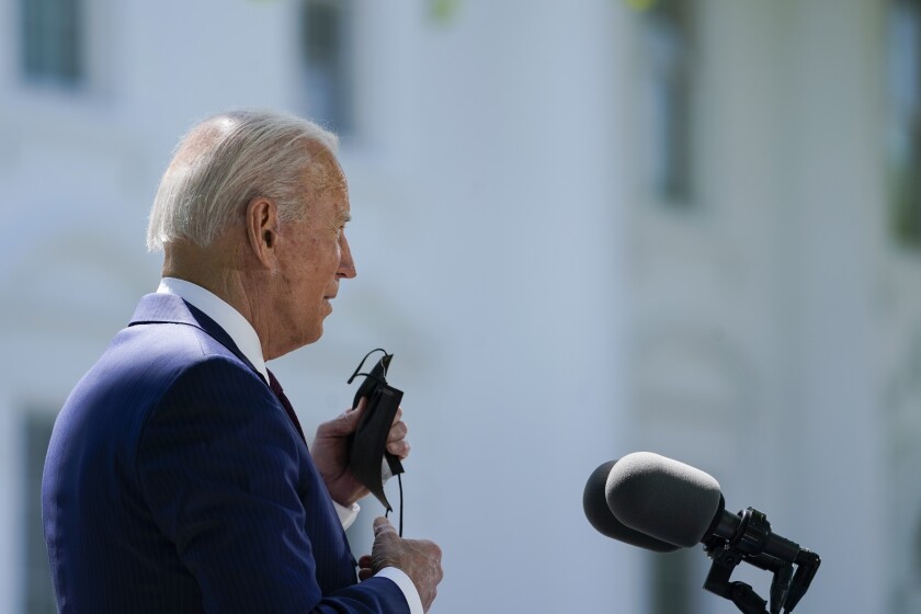 A profile view of President Biden standing before the podium on the North Lawn of the White House 