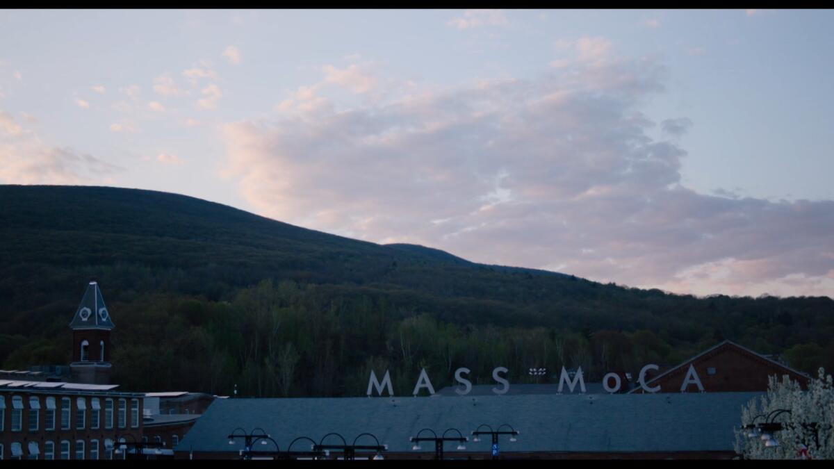 A view of MASS MoCA's sign on its roof at dusk
