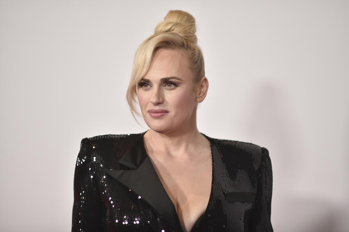 A woman with a bun of blond hair piled atop her head and wearing a sparkly black blazer