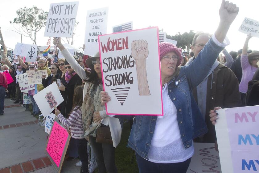 Hundreds of demonstrators hold signs as they participate in the Laguna Beach Women’s March at Main Beach in Laguna Beach on Saturday.