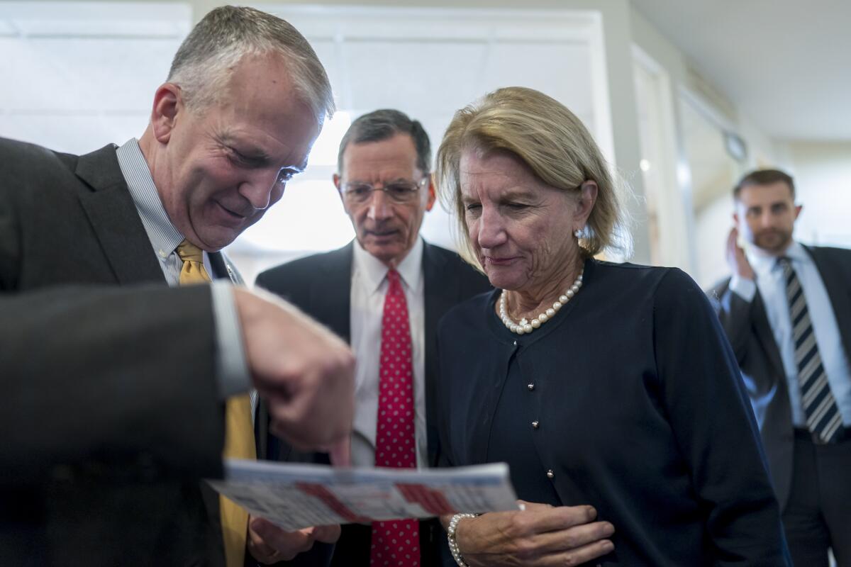 From left, Sen. Dan Sullivan, R-Alaska, Sen. John Barrasso, R-Wyo., and Sen. Shelley Moore Capito, R-W.Va., confer just before a news conference to discuss their efforts to rescind recent Biden administration rules on the National Environmental Policy Act, at the Capitol in Washington, Tuesday, Aug. 2, 2022. (AP Photo/J. Scott Applewhite)