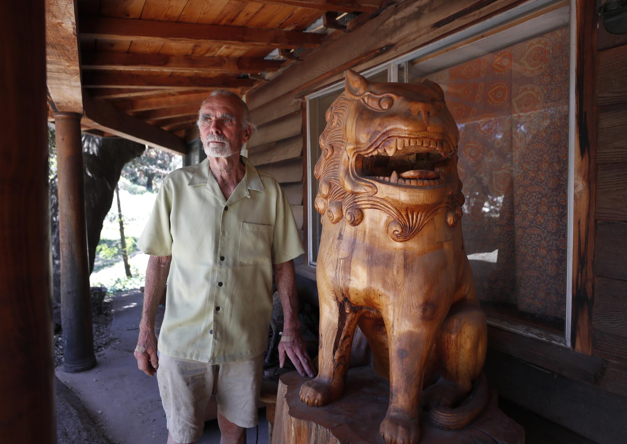 Duncan McFetridge next to a lion he carved