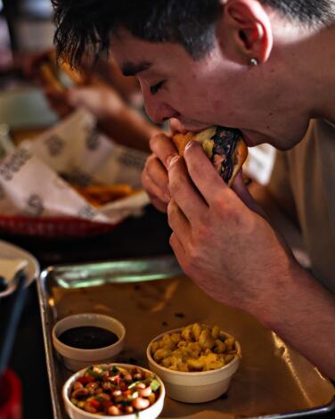 A hungry guest takes a bite of a brisket sandwich at Bludso's BBQ.