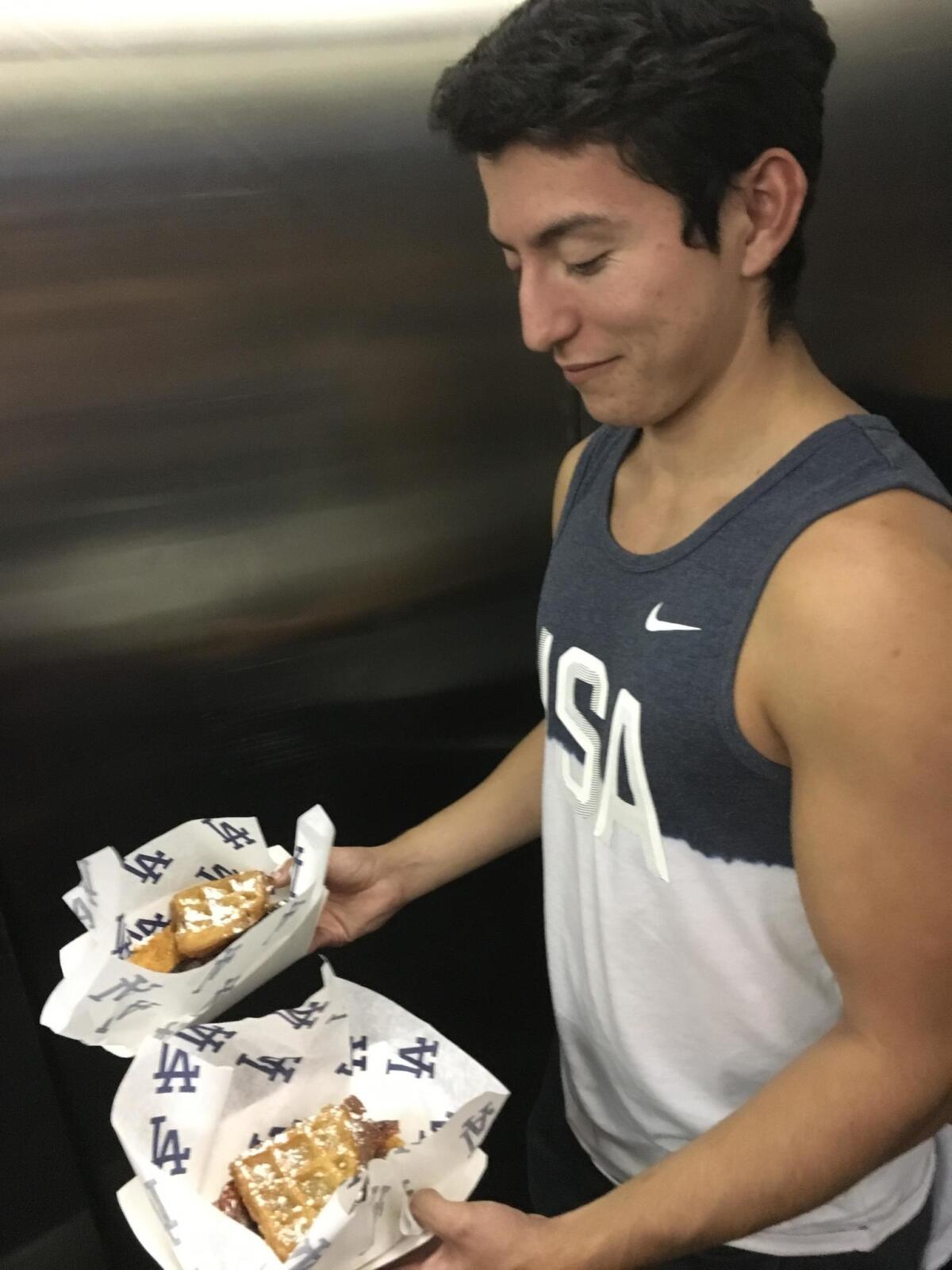 Cameron Romo carries two chicken waffle sandwiches.