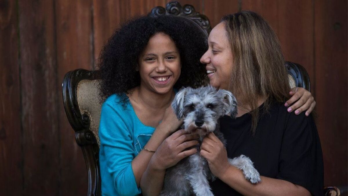 Chloe Fernandez, 11, her dog, Abby, and her mother, Leslie Mota, relax at their home in Huntington Beach.