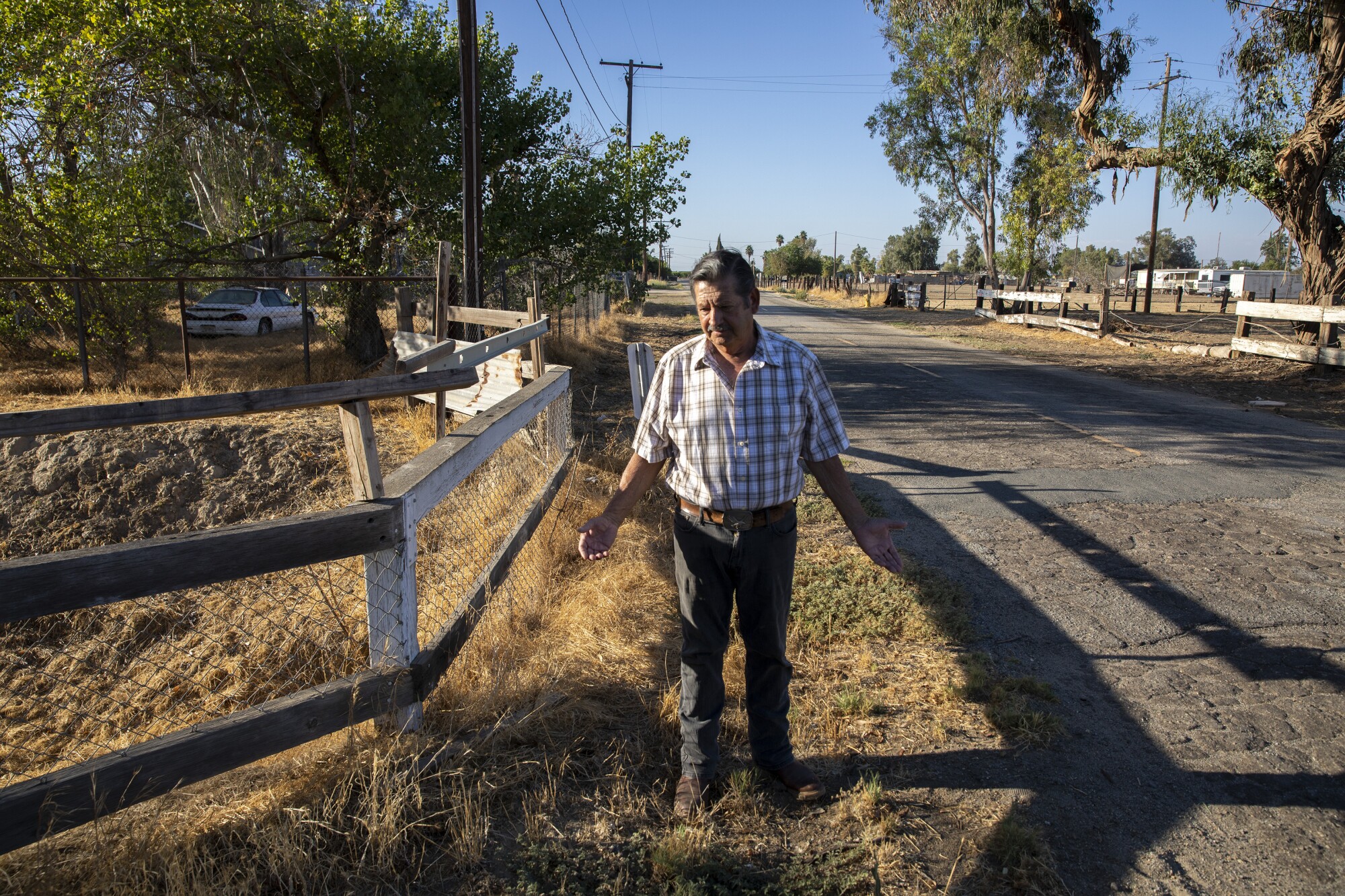 Jesús Benítez stands near a spot where an underground pipe carrying city water ends just 100 feet from his home