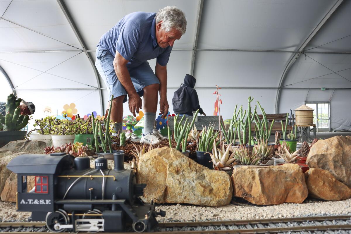 Claude Mueller sets up a train track landscape display for the HomeGrownFun at the Del Mar Fairgrounds.