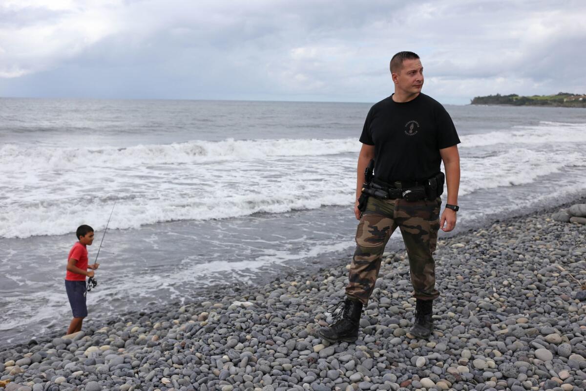 A police officer from Saint-Benoit's gendarmerie looks Saturday for debris from the ill-fated Malaysia Airlines Flight MH370 on Reunion Island in the Indian Ocean.