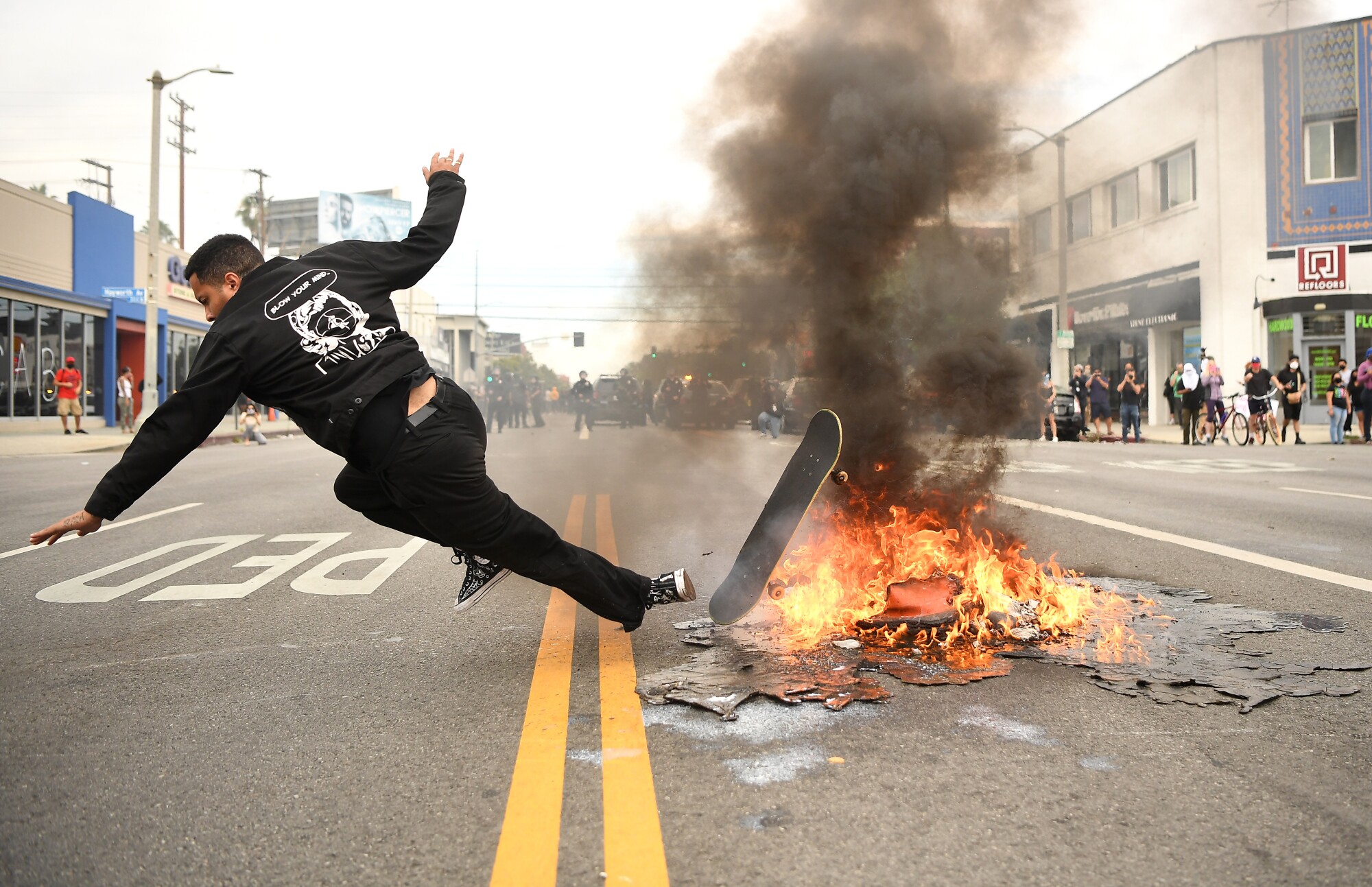 A skateboarder falls over a small fire set by protesters on 3rd Street in Los Angeles.