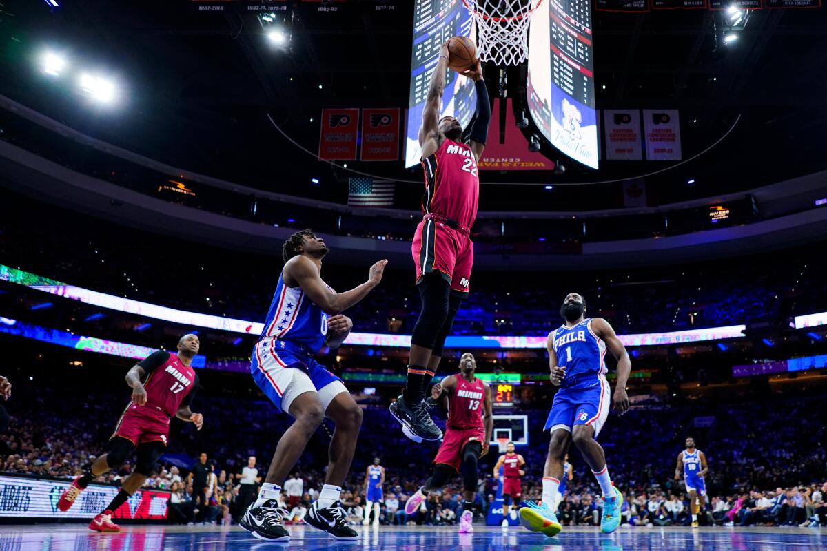 Jimmy Butler del Heat de Miami clava el balón sobre Tyrese Maxey y James Harden de los 76ers 