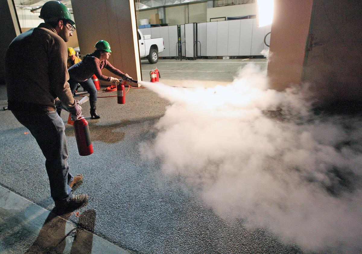 Glendale residents Reza Seraji and Ani Aharonian try their hand at putting out a fire with extinguishers during a CERT training program on Thursday, February 6, 2014.