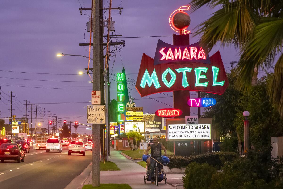 A person rides along Beach Boulevard, past motels and hotels in Anaheim in this 2019 file photo.