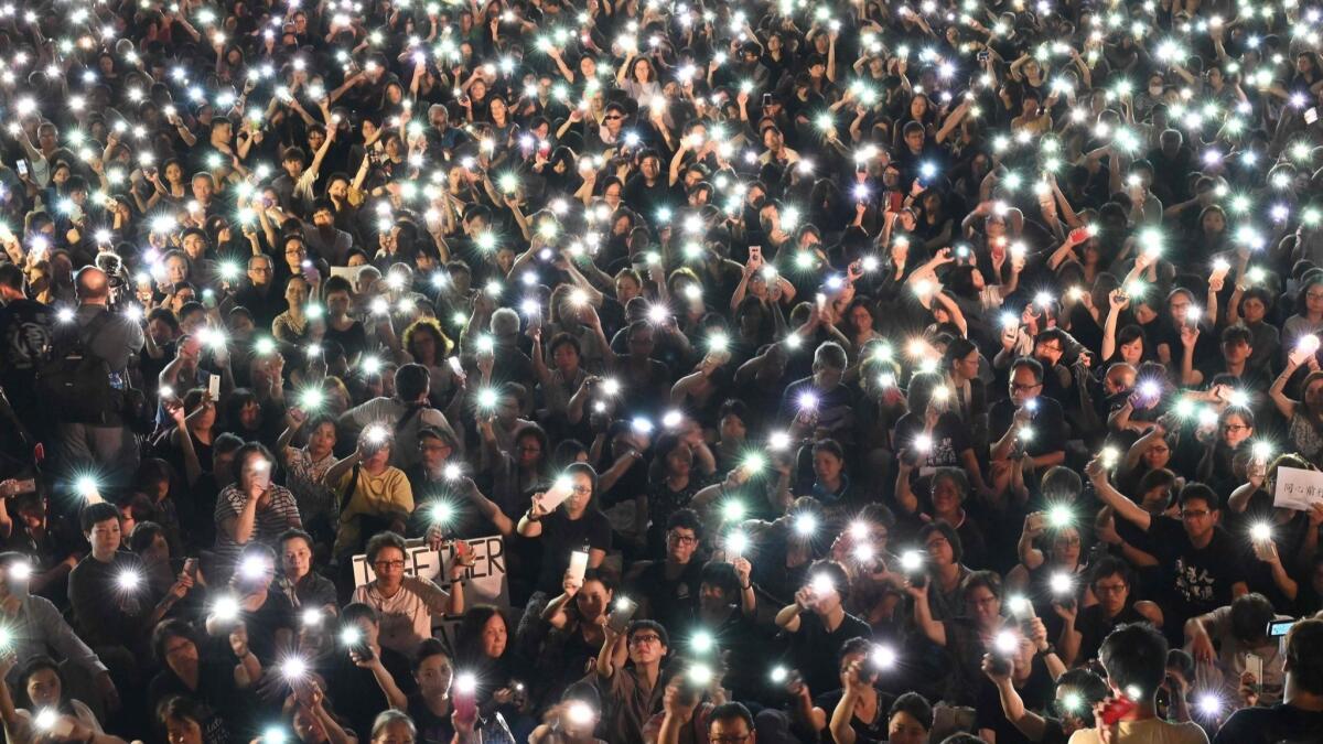 Demonstrators hold up their phones during a rally organized by Hong Kong mothers in support of extradition-law protesters, in Hong Kong on July 5, 2019.