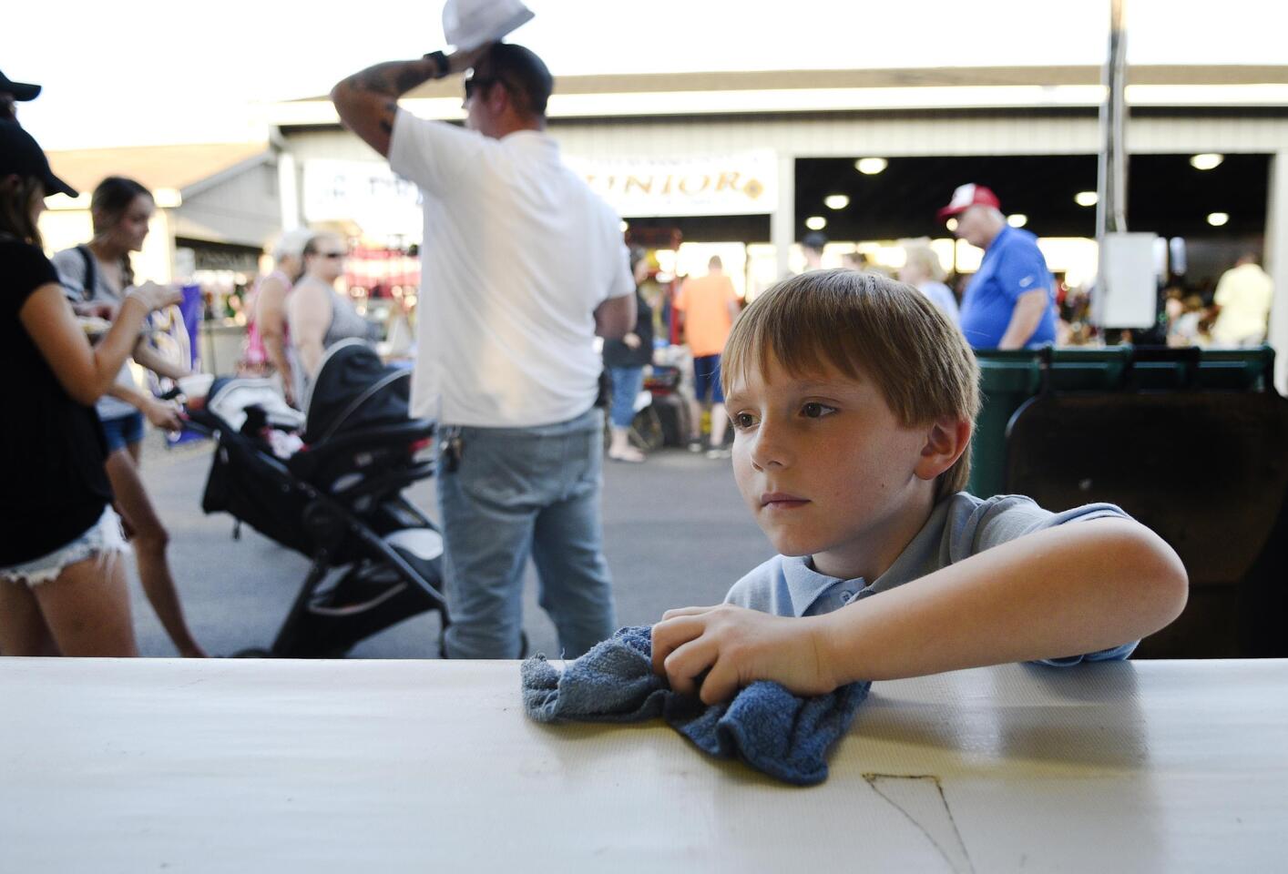 Austin Warner, 6, helps out by wiping down the counter at the Winfield fire company's funnel cake stand at the fire company's annual carnival Wednesday, July 10, 2019.