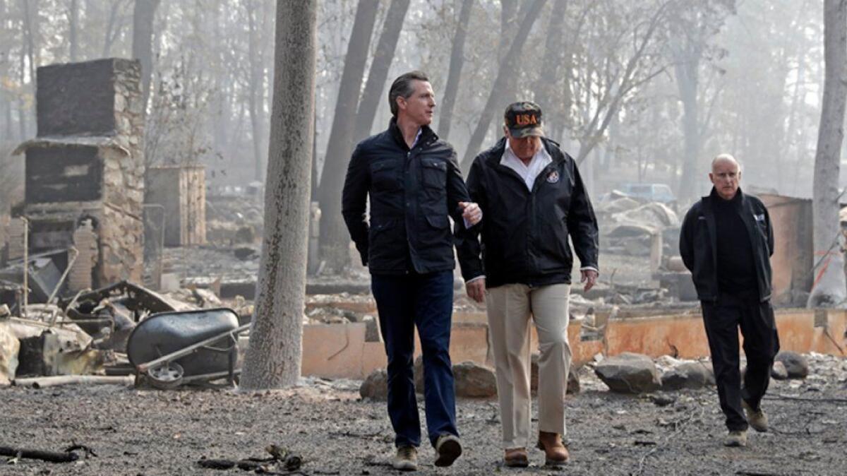 Then-Gov.-elect Gavin Newsom walks with President Trump and Gov. Jerry Brown last year in a neighborhood destroyed by the Camp fire in Paradise, Calif.