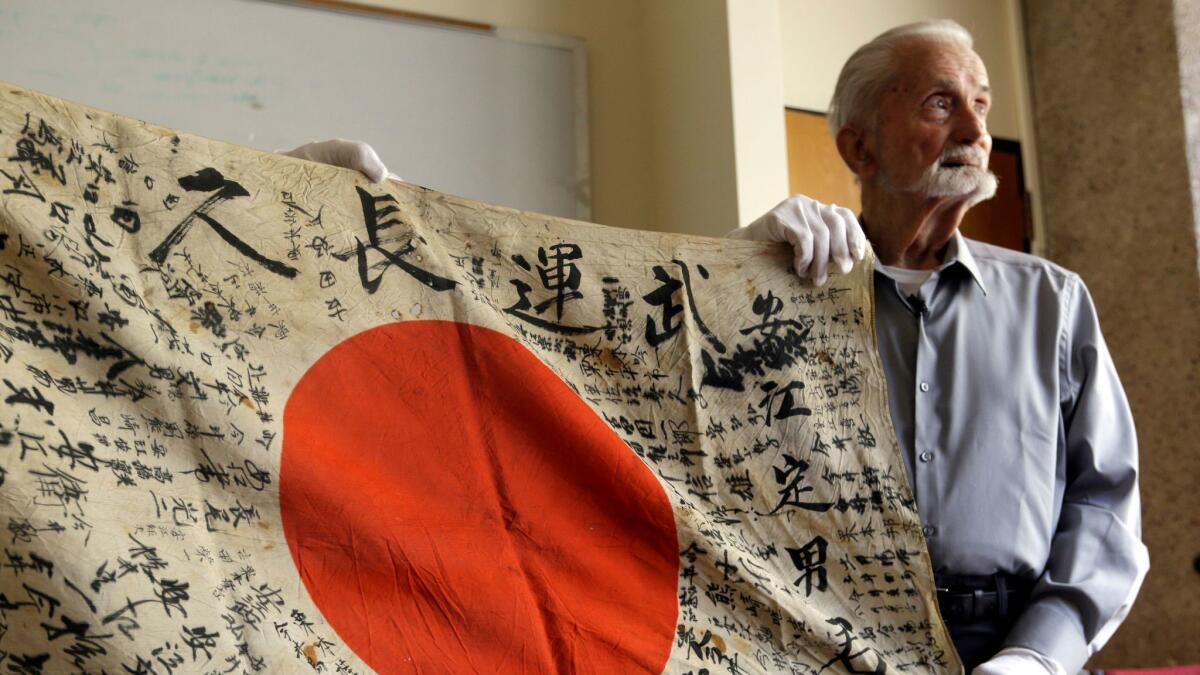 World War II veteran Marvin Strombo holds up the Japanese flag he will return to the family of a soldier killed in the war.