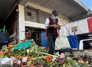 A man walks by a pile of discarded produce.