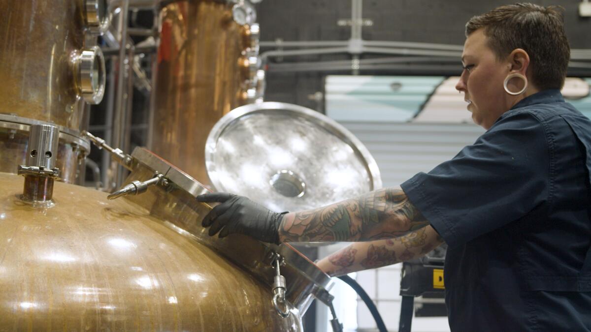 A distillery staffer works at a vat to make hand sanitizer