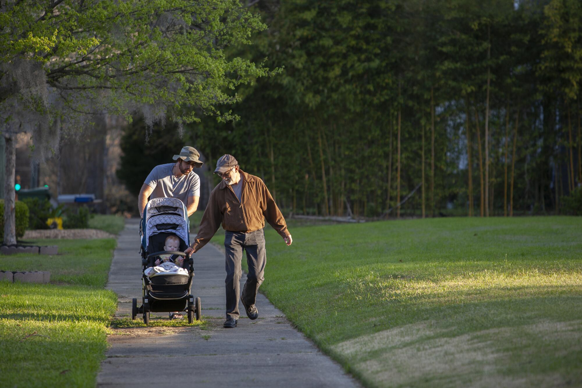 Two men with children in a stroller at a park