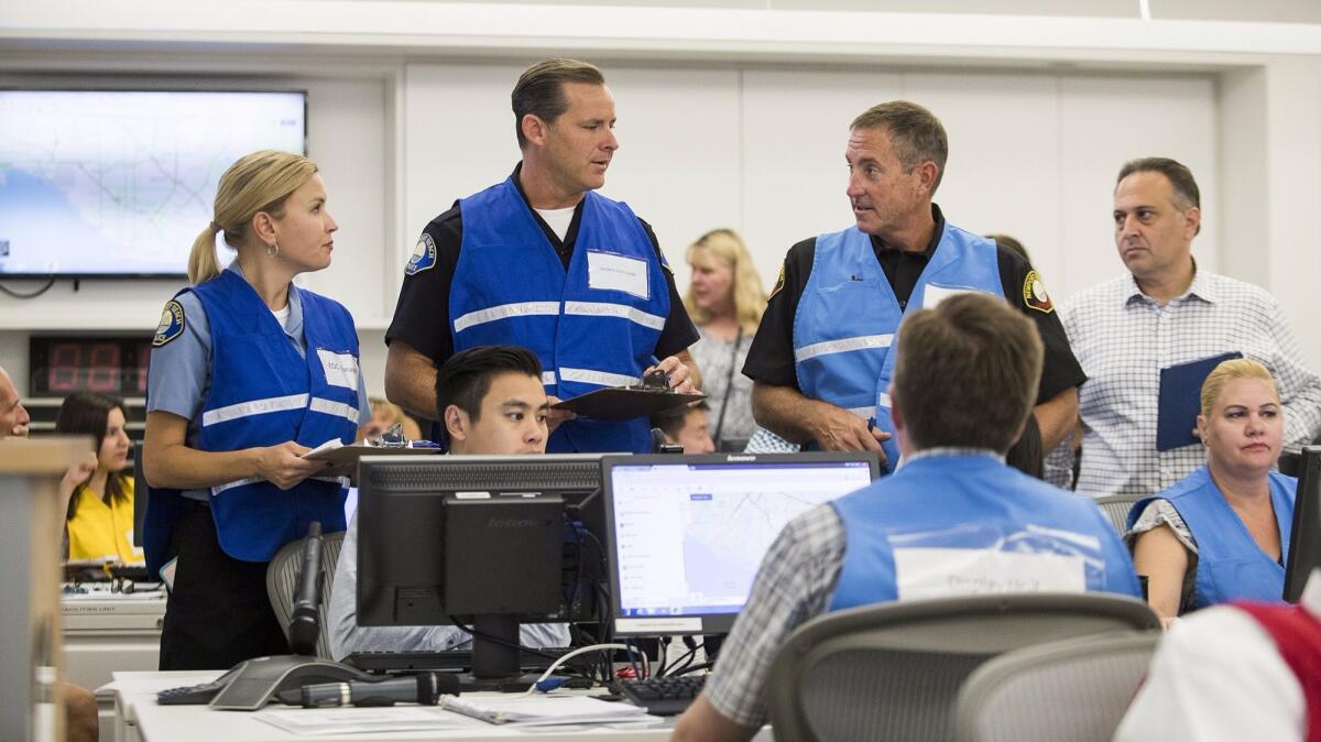 Newport Beach Police Chief Jon Lewis, center left, talks with lifeguard Battalion Chief Mike Halphide during an exercise responding to simulated terrorist attacks Wednesday.