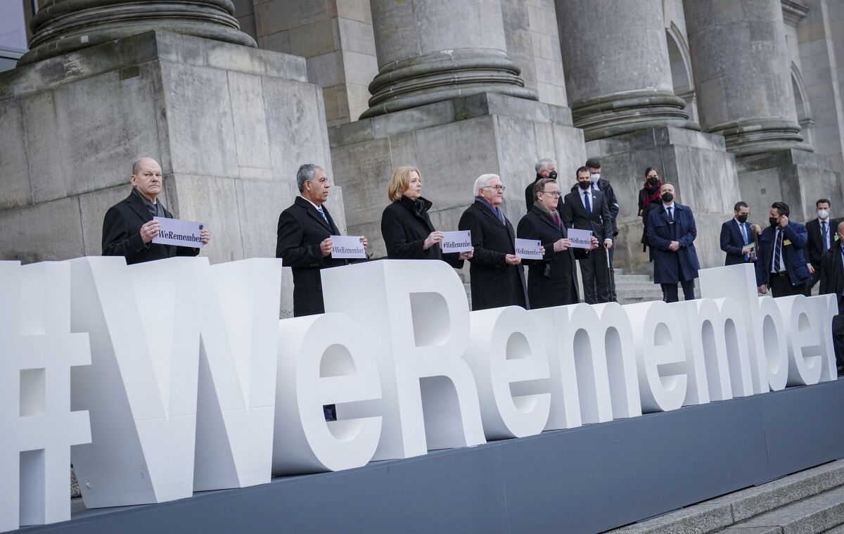 People stand behind a three-dimensional sign reading #WeRemember.