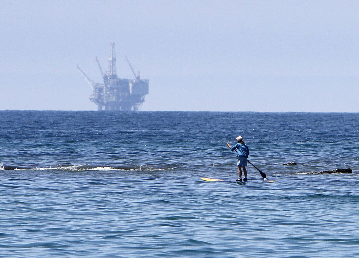 FILE - A person paddle boards as the Refugio State Beach reopens after a massive oil spill, Friday, July 17, 2015, in Santa Barbara, Calif. A proposal to replace a pipeline near Santa Barbara that was shut down in 2015 after causing California's worst coastal oil spill in 25 years is inching through a government review, even as the state moves toward banning gas-powered vehicles and oil drilling. (Daniel Dreifuss/The Santa Maria Times via AP, File)