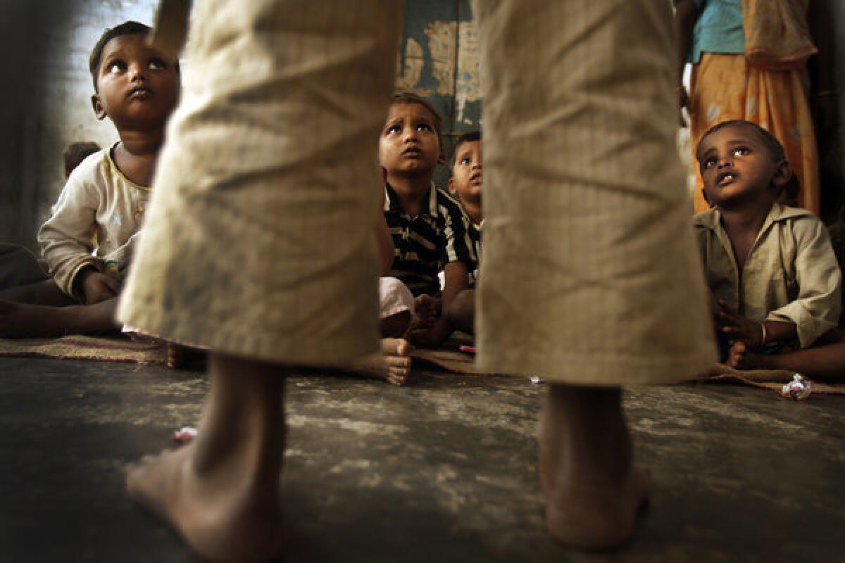 Children listen as they await a supplemental midday meal at a community center on the outskirts of Lucknow.