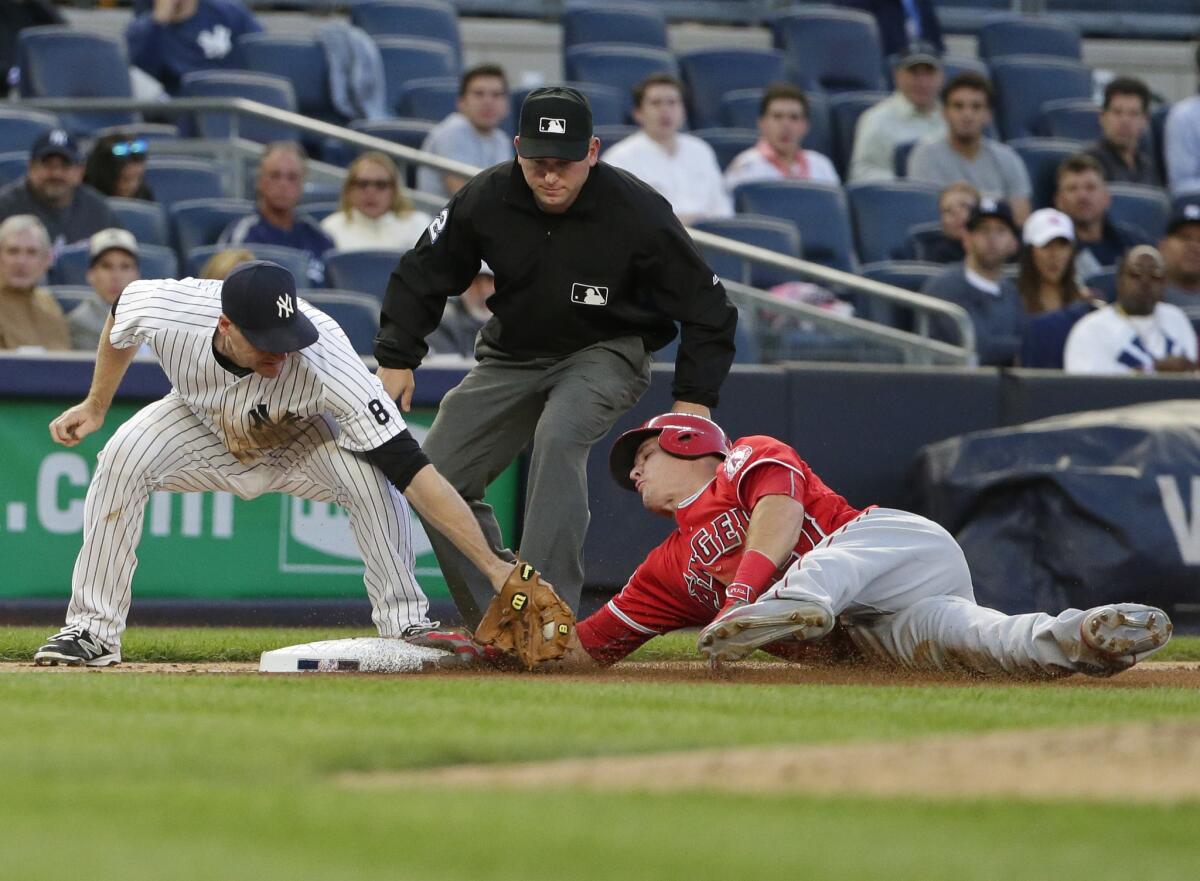 Angels outfielder Mike Trout, right, steals third base as Yankees third baseman Chase Headley attempts to tag him out in the fourth inning.