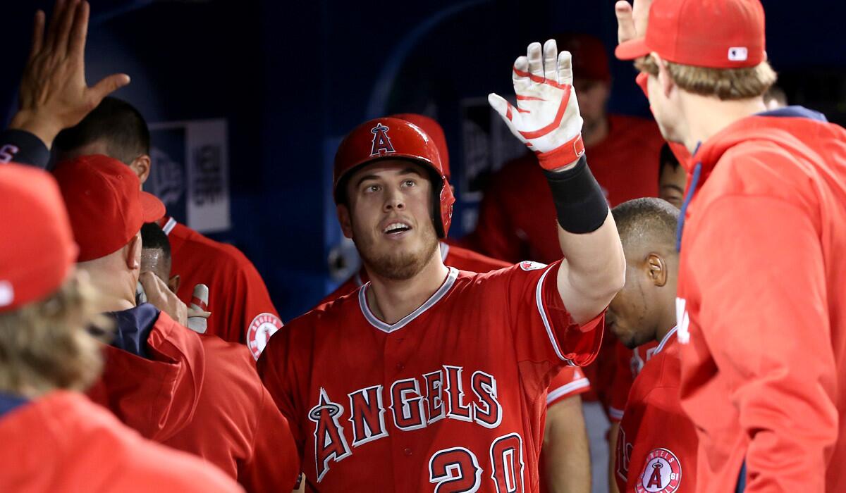 Angels first baseman C.J. Cron is congratulated by teammates in the dugout after hitting a solo home run in the third inning against the Blue Jays on Saturday in Toronto.