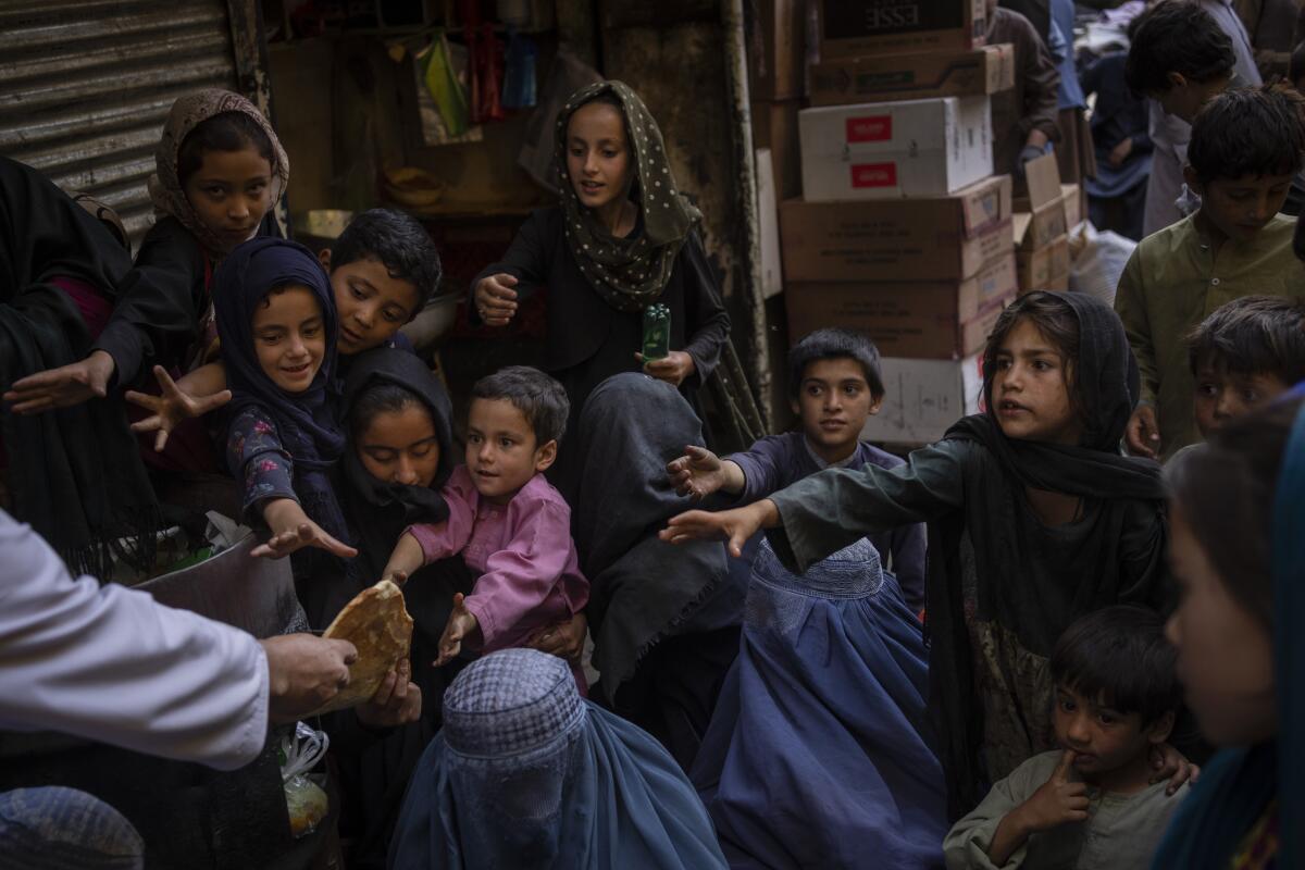 Mujeres y niños afganos reciben donaciones de pan en la Ciudad Vieja de Kabul