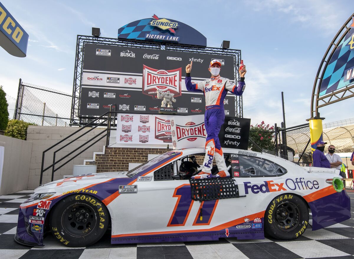 Denny Hamlin stands on his car after winning the NASCAR Cup Series auto race at Dover International Speedway, Saturday, Aug. 22, 2020, in Dover, Del. (AP Photo/Jason Minto)