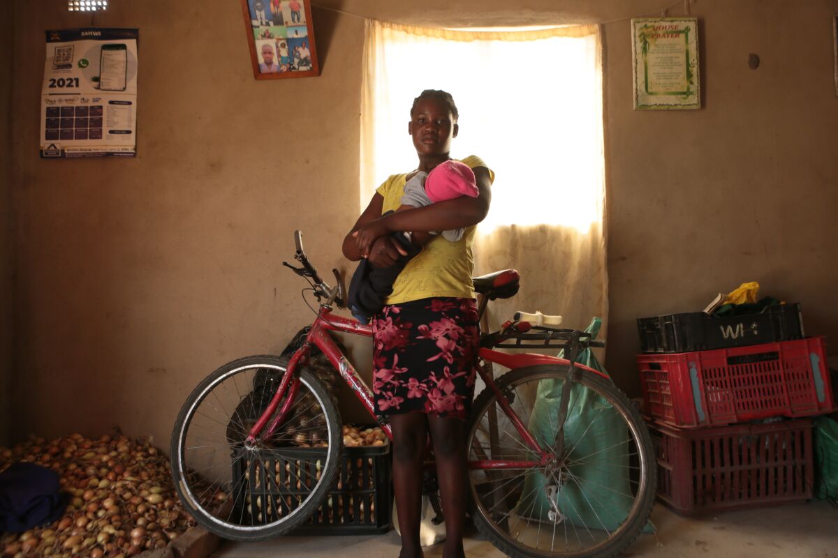 Virginia Mavhunga, a 13-year-old teenage mother, hold her child at her home in Murehwa, 80 kilometres (50 miles) northeast of Zimbabwe's capital Harare, Saturday, Dec. 11, 2021. Virginia dropped out of school after falling pregnant and becoming the subject of gossip and consternation in a community yet to adjust to the sight of a pregnant girl in school uniform. (AP Photo/Tsvangirayi Mukwazhi)