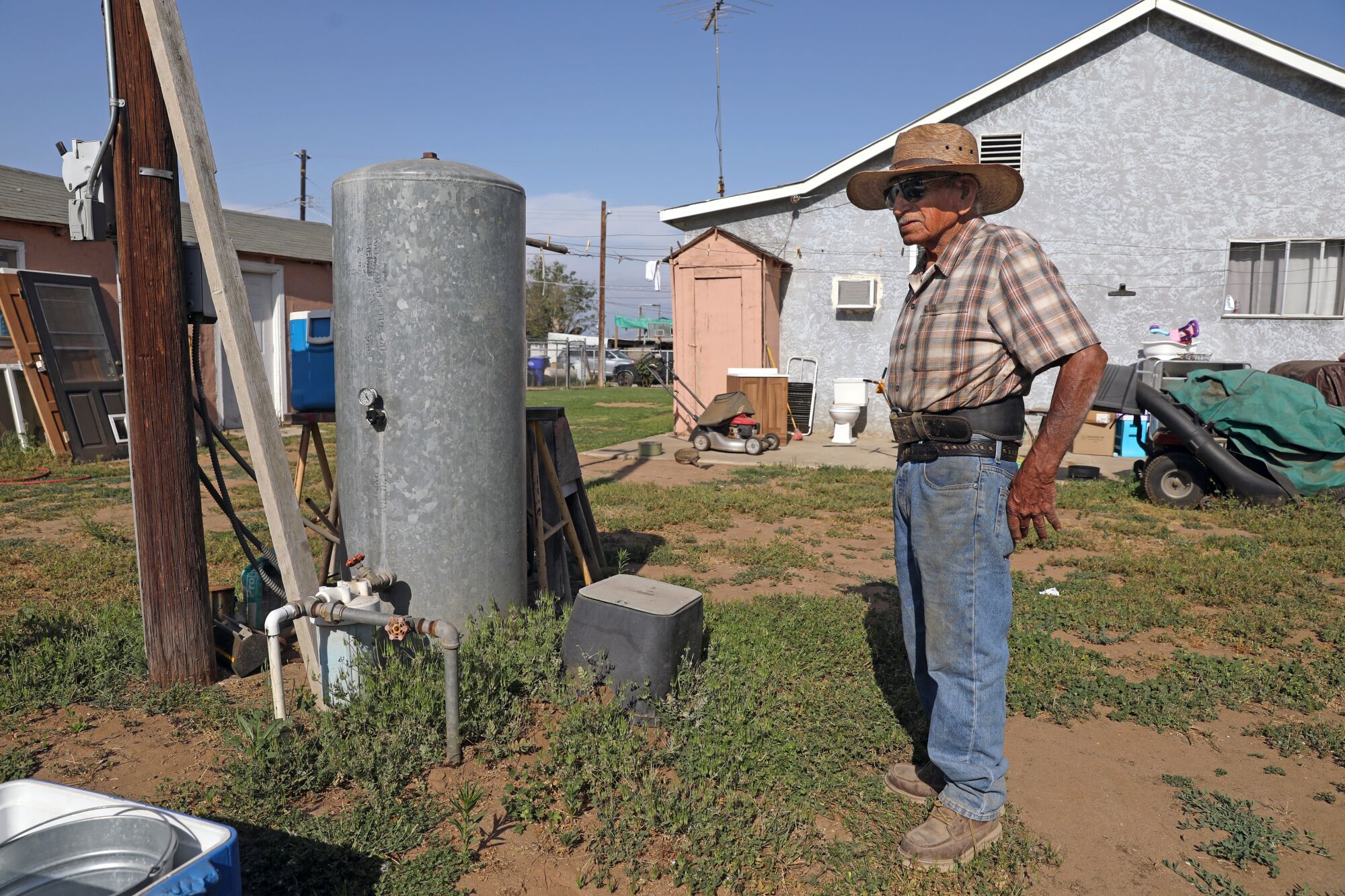 Rodolfo Romero near his 60-foot deep water well and pressure tank that provides water to the home.