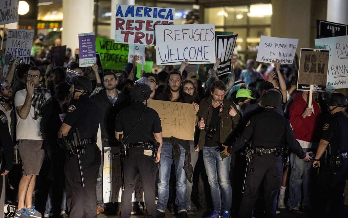 Protesters are held back by airport police on Sunday at LAX.