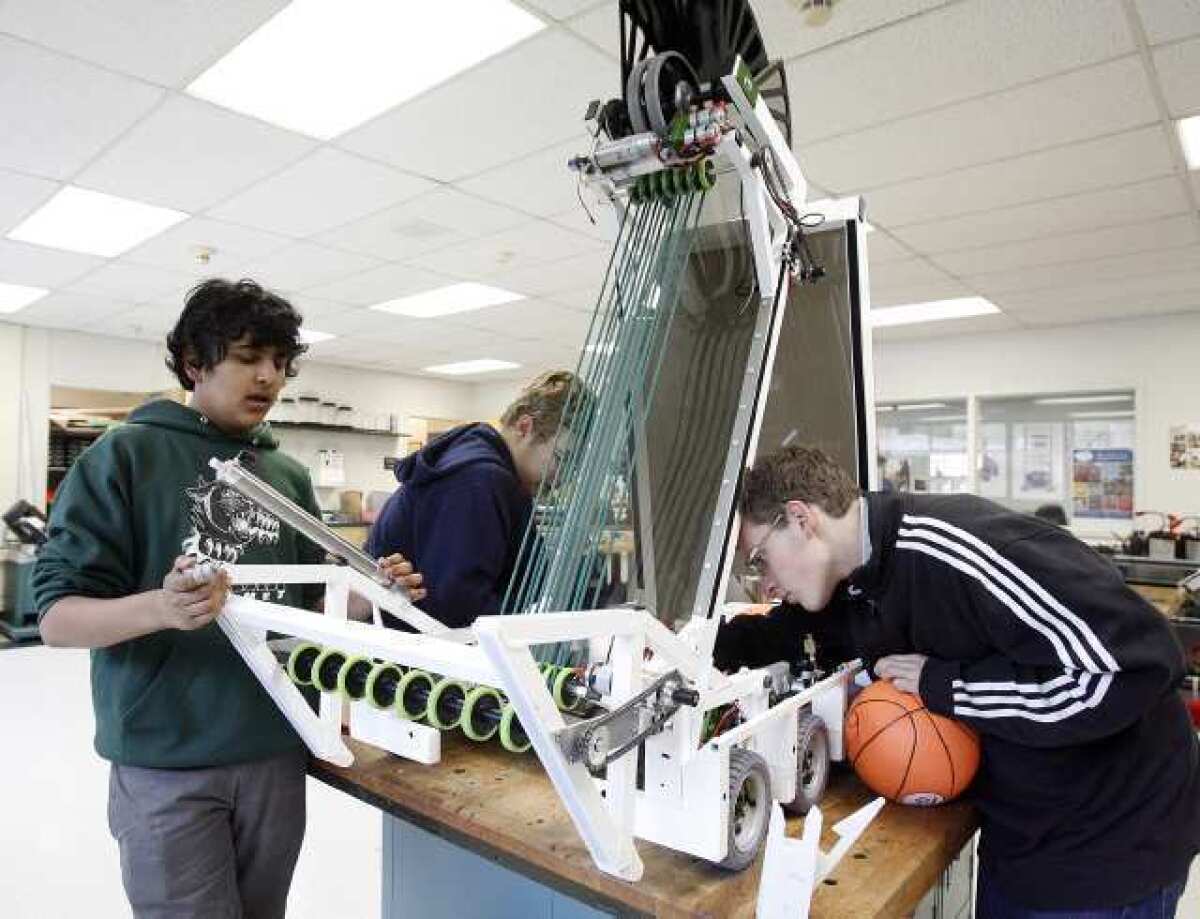 Saikiran Ramanan, 15, Corey Hoard, 17, and Guy Burstein, 16, of Circuit Breakers 696, after 15 straight hours, continue work on their robot at Clark Magnet High School in La Crescenta. The school received a 920 API score.
