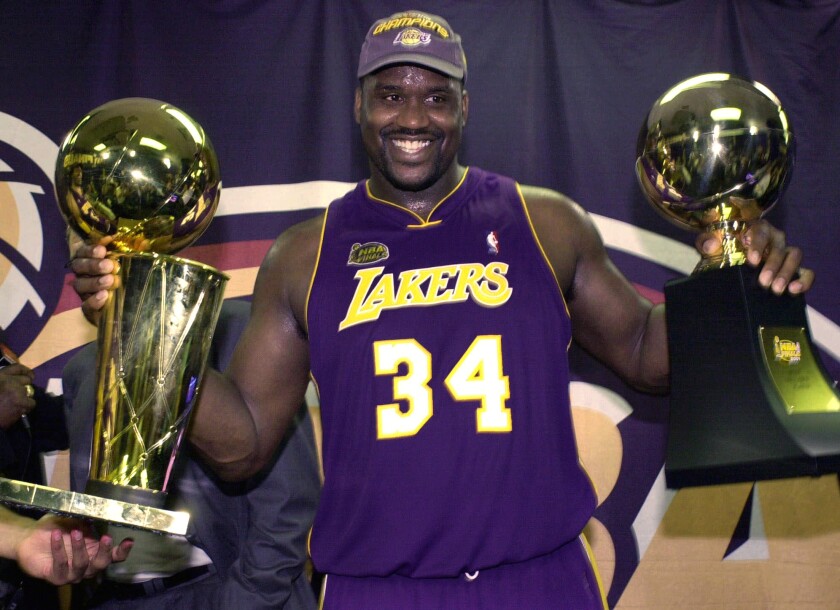 Shaquille O'Neal holds up the MVP trophy, right, and the championship trophy after the Lakers won their second straight NBA title in 2001.