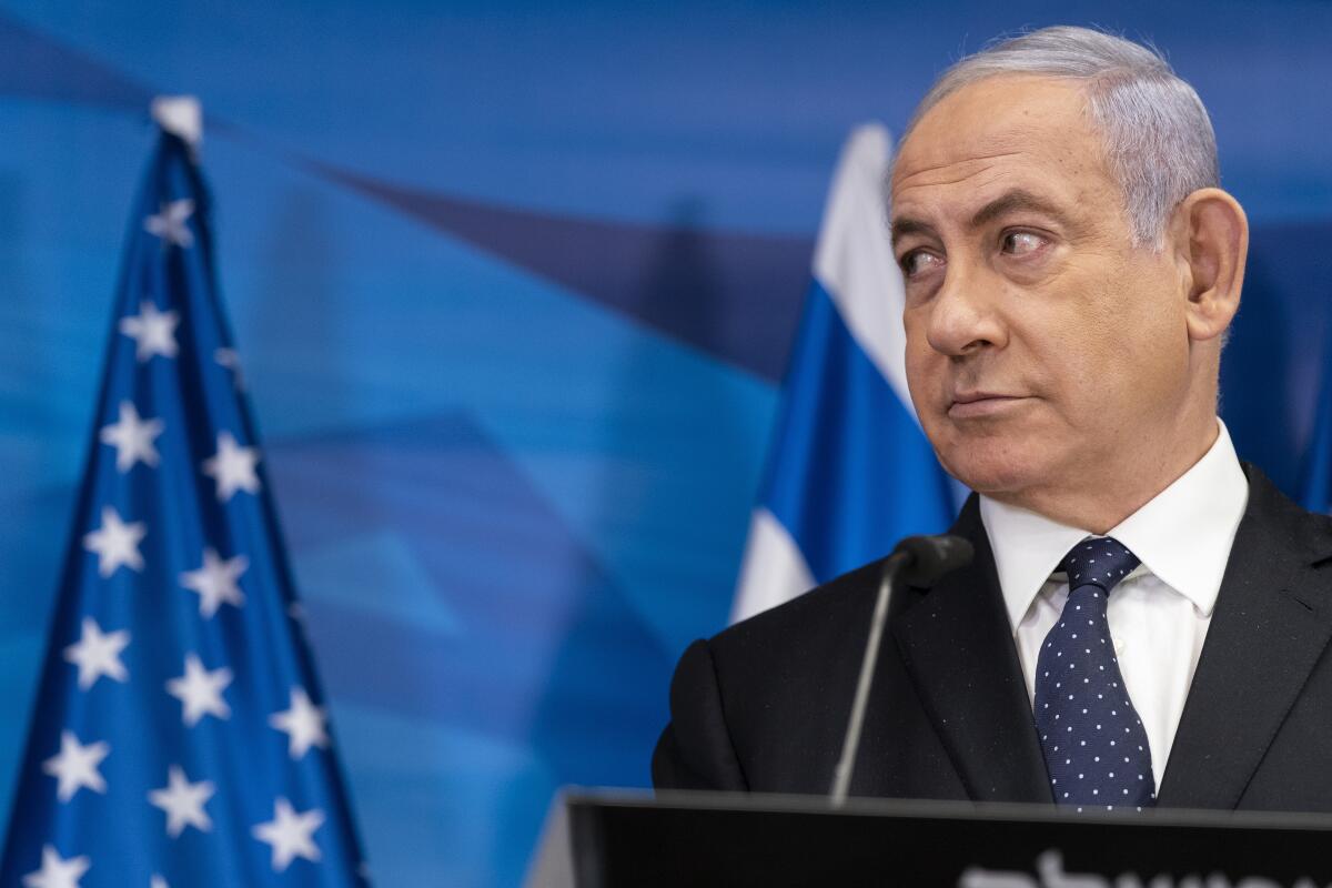 Benjamin Netanyahu stands at a podium behind a microphone.
