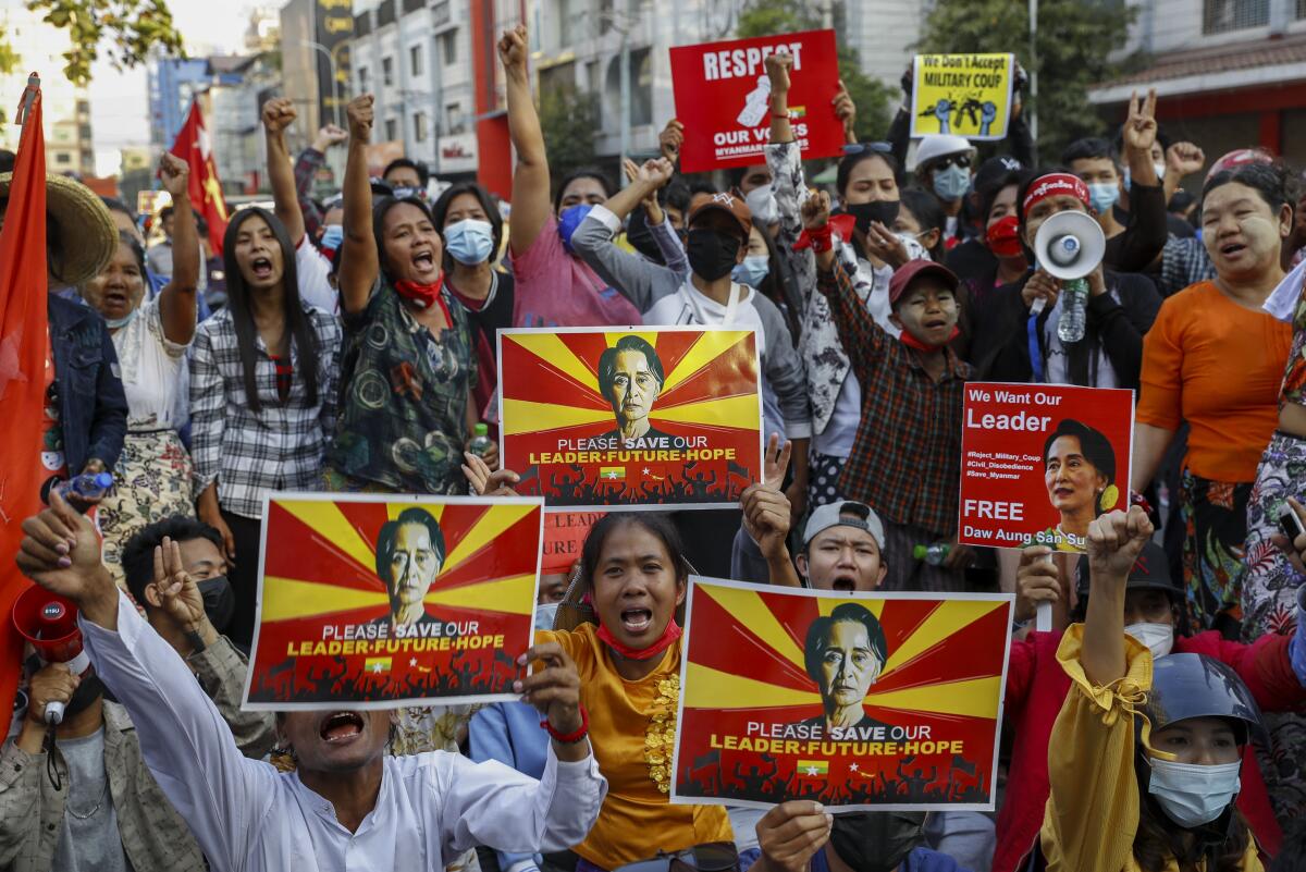 Demonstrators hold signs bearing the image of deposed Myanmar leader Aung San Suu Kyi