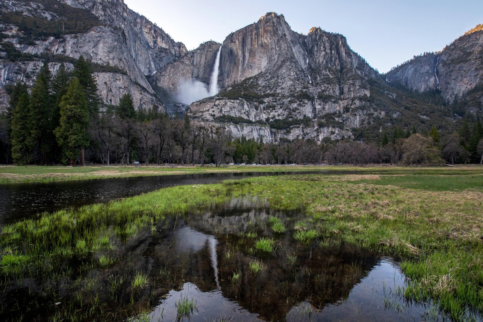 The waterfall is reflected in water in the meadow in the Yosemite Valley.