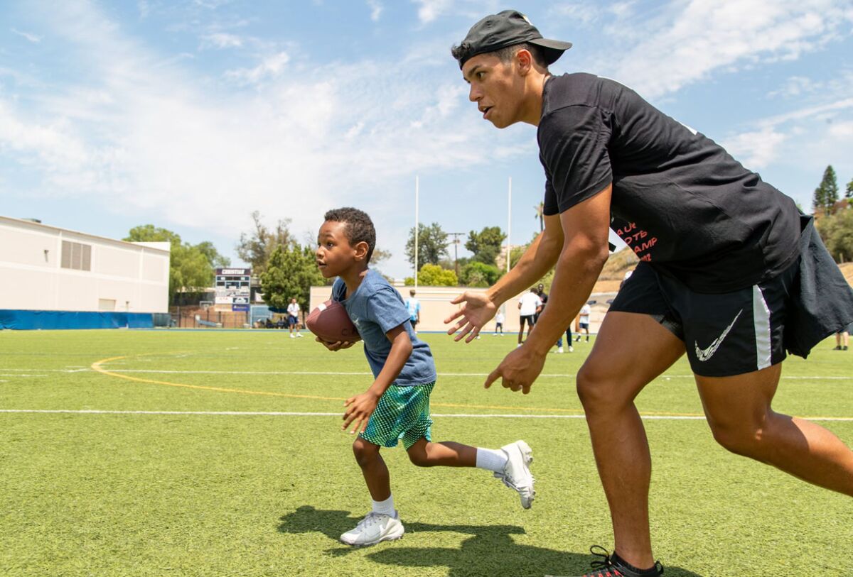 Jesse Matthews encourages a youngster during the San Diego State wide receiver's inaugural football camp for kids.