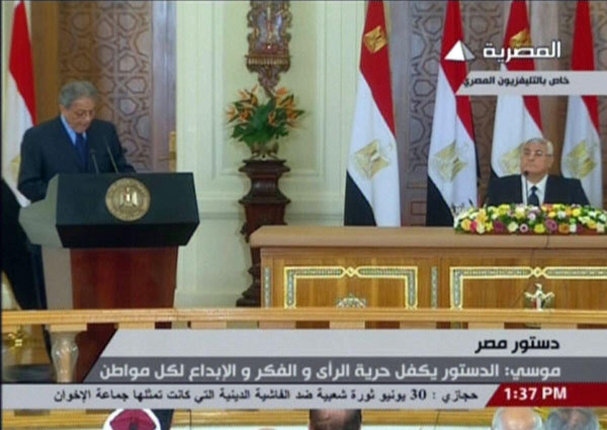 In an image from Egyptian state TV, constitutional committee Chairman Amr Moussa, left, announces the date for a referendum on a new constitution as interim President Adly Mansour listens.